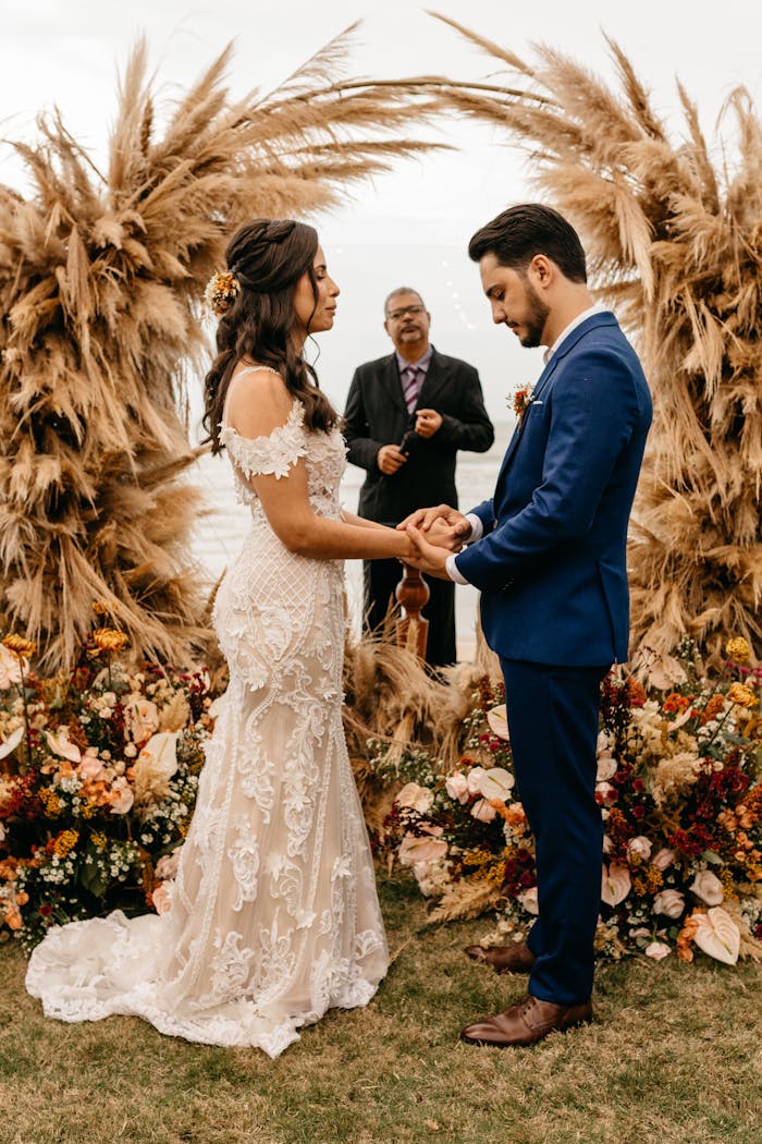 Bride and groom exchanging vows in a scenic beachside ceremony with floral decor.